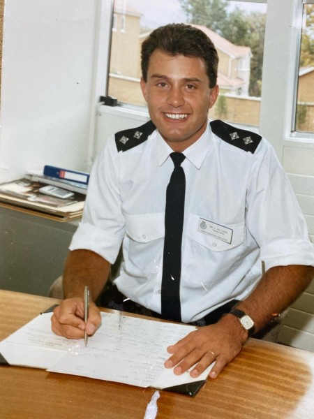 David Williams pictured at the start of his career as a younger man. He is smiling while writing down notes on pieces of paper