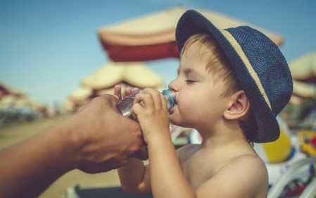 child drinking water on beach